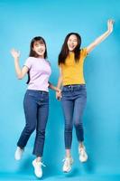 retrato de corpo inteiro de duas lindas garotas asiáticas em um fundo azul