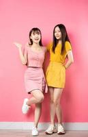 retrato de duas lindas garotas asiáticas posando em fundo rosa foto