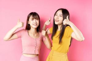 retrato de duas lindas garotas asiáticas posando em fundo rosa foto