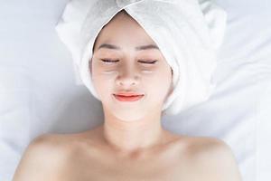 mulher asiática fazendo tratamentos de beleza, tratamentos de spa e aplicando creme no rosto foto