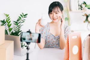Mulher de negócios asiática está usando smartphones para transmitir ao vivo a venda de cosméticos em sites de redes sociais e sites de comércio eletrônico. foto