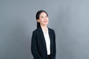 mulher asiática feliz com uma cara feliz em roupas de escritório em fundo cinza foto