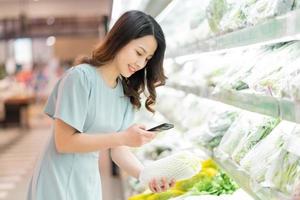 a jovem está escolhendo comprar legumes no supermercado foto