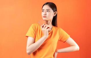 imagem de jovem asiática segurando um smartphone em fundo laranja