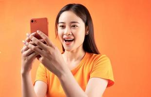 mulher asiática segurando o smartphone na mão com uma expressão de surpresa