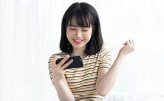 linda mulher asiática jogando no smartphone no quarto