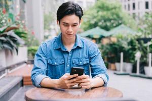jovem asiático usando smartphone em uma cafeteria foto