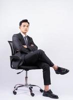 jovem empresário asiático sentado na cadeira no fundo branco foto