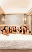 uma grupo do ásia Adolescência meninas estão ficando acima atrasado com seus amigos em uma luxuoso branco cama foto