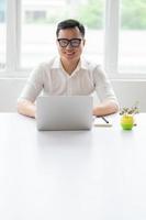 jovem empresário asiático trabalhando com laptop no escritório foto