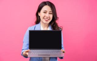 mulher de negócios asiáticos segurando laptop sobre fundo rosa foto