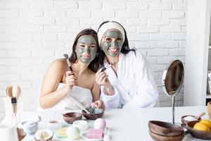 duas lindas mulheres aplicando máscara facial se divertindo foto