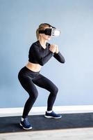 jovem loira usando óculos de realidade virtual agachada em casa
