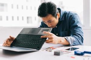 o homem asiático estava retirando um computador quebrado para consertá-lo foto