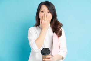 linda empresária asiática segurando uma xícara de café de papel na mão, ela cobriu a boca com a mão em surpresa foto