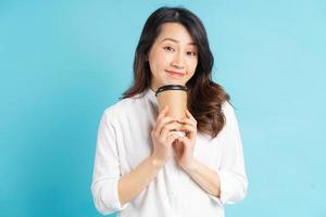linda empresária asiática segurando uma xícara de café de papel na mão