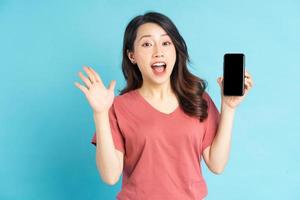 linda mulher asiática segurando o smartphone na mão com uma expressão alegre foto