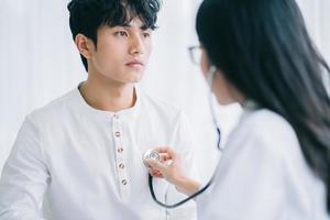 médica asiática está ouvindo os batimentos cardíacos para diagnosticar a doença de um paciente foto