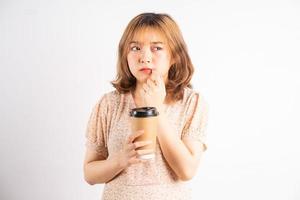 jovem asiática segurando uma xícara de café com expressão no fundo foto