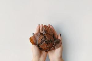 muffin de chocolate nas mãos da mulher.