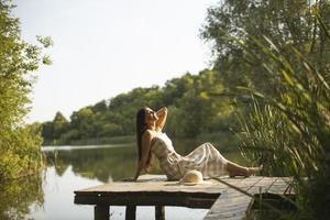 jovem relaxante no cais de madeira no lago foto