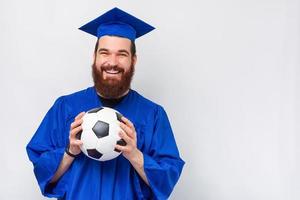 homem barbudo sorridente e alegre solteiro segurando uma bola de futebol foto