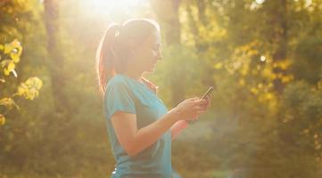 foto de jovem esportista usando aplicativo de smartphone para exercícios ao pôr do sol
