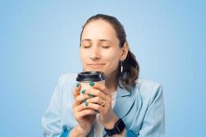 fechar retrato de mulher jovem cheirando seu saboroso café matinal foto