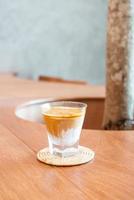 copo de café sujo ou leite frio coberto com uma dose de café expresso quente em uma cafeteria foto