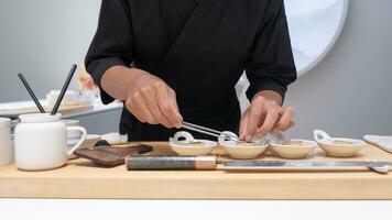 profissional chefe de cozinha preparando e cozinhando cru fresco peixe ingrediente em a mesa com faca para delicioso Sushi e sashimi refeição, pessoa fazer luxo omakase bem jantar japonês Comida restaurante jantar foto