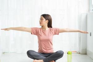 mulher asiática praticando ioga em casa