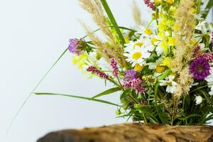 uma seco toco, árvore latido e uma ramalhete do selvagem flores dentro uma pequeno vidro vaso. à moda aparência, disposição, personalidade. foto