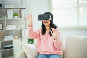 ásia mulher sorrir e jogar vr jogo, 3d dispositivo Novo inovação óculos para entreter dentro vivo quarto às lar, ásia mulher alegre dentro casa em feriado. feliz mulher jogando metaverso vr tecnologia conceito. foto