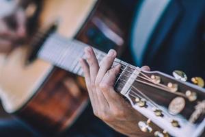 feche a mão tocando violão foto