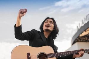 homem canta música e toca guitarra ao ar livre foto