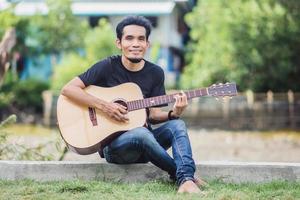 homem tocando guitarra ao ar livre feliz no verão foto