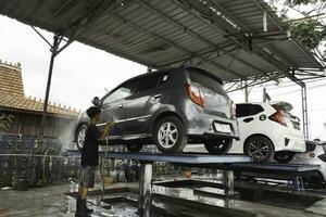 uma cinzento carro é em hidráulico ser lavar dentro uma serviço carro lavar estação. foto