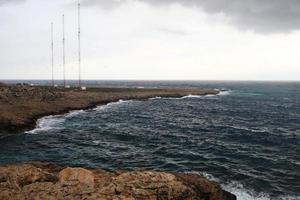 ondas batendo nas falésias rochosas de uma praia localizada em chipre, esse clima pode ser perigoso para esportes aquáticos, mas ao mesmo tempo as ondas e seus respingos são bonitos e selvagens foto