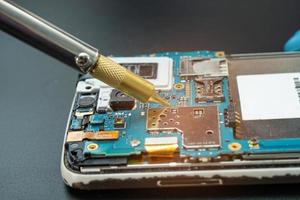 técnico que repara dentro do telefone móvel com ferro de solda circuito integrado. o conceito de dados, hardware, tecnologia. foto
