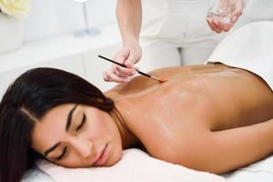 mulher recebendo tratamento de massagem nas costas com escova de óleo no centro de bem-estar do spa
