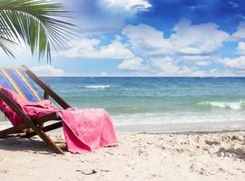 toalha em cadeiras de praia em bela praia tropical foto