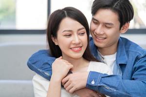 jovem casal asiático se abraçando alegremente em casa
