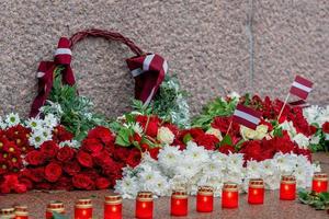 letônia 100 anos. composições de flores vermelhas e brancas no monumento da liberdade na cidade de riga, letônia foto