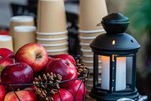 Lanterna de vela brilhante e cesta de maçãs na mesa do mercado de natal em riga, letônia, foco seletivo