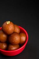 gulab jamun em tigela sobre fundo preto. sobremesa indiana ou prato doce. foto