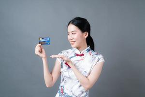 Mulher asiática usando vestido tradicional chinês com a mão segurando um cartão de crédito foto