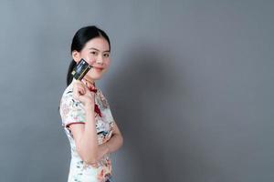 Mulher asiática usando vestido tradicional chinês com a mão segurando um cartão de crédito foto