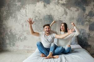 jovem feliz sorridente casal sentado em cama às casa foto