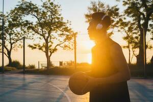 Preto homem fazendo Esportes, jogando basquetebol em nascer do sol, ativo estilo de vida, ensolarado verão manhã foto