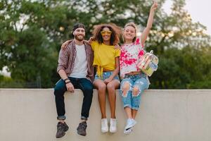 feliz jovem companhia do sorridente amigos sentado dentro parque foto